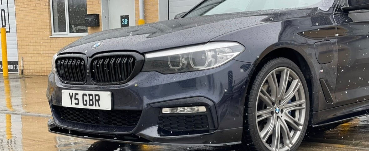 BMW 5 Series G30 G31 Body Kit showcased on a stylish gray car with alloy wheels in the rain.