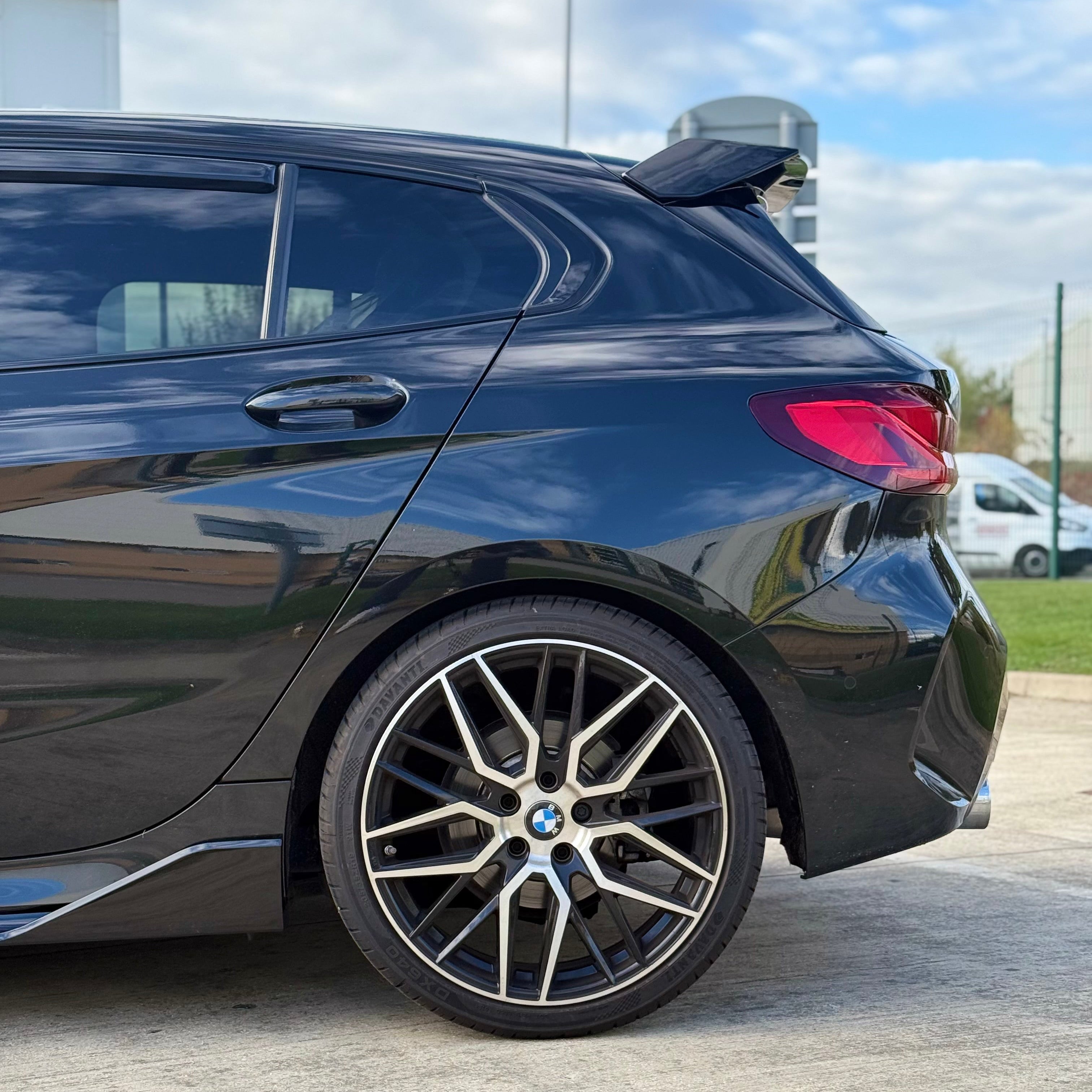 BMW F40 Gloss Black Body Kit showcased on a sleek black hatchback with stylish alloy wheels.