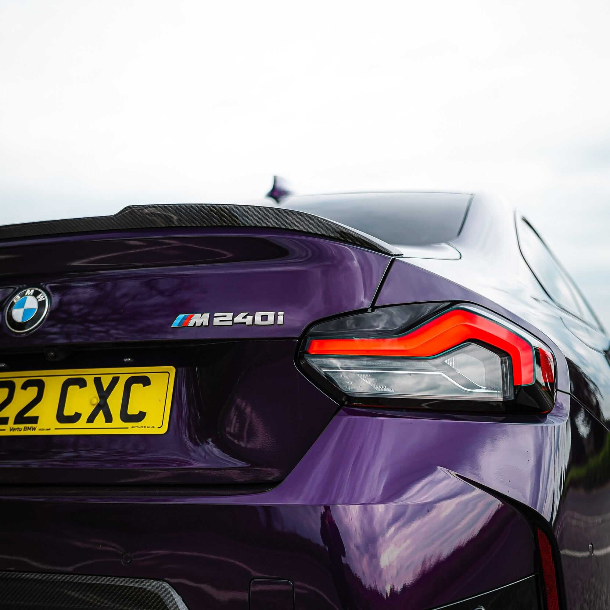 BMW G87 G42 Carbon Fibre Spoiler V2 installed on a BMW M240i, showcasing a sleek and aggressive rear design.