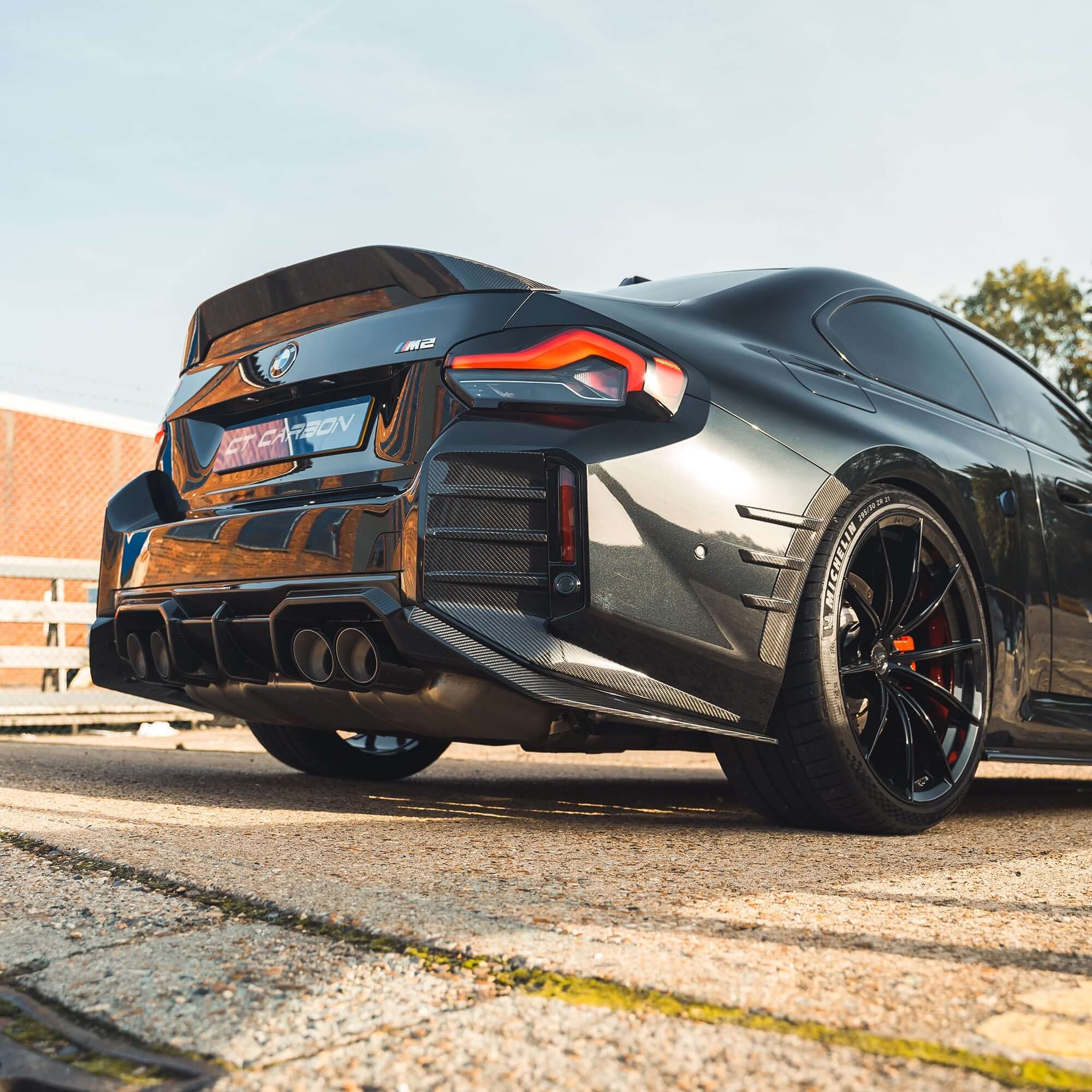 BMW G87 M2 Carbon Fibre Diffuser installed on a sleek black BMW M2, showcasing its aggressive rear design.