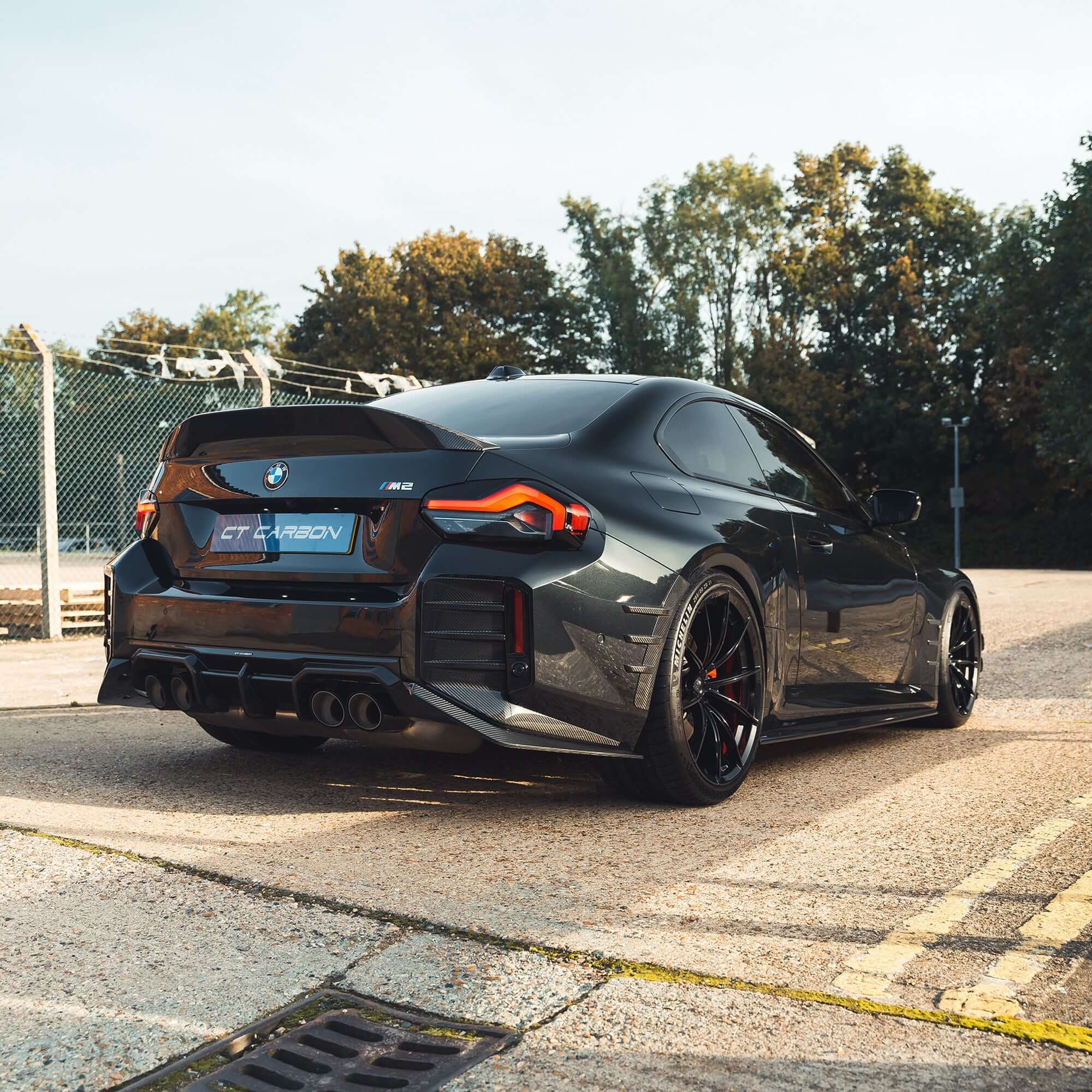 BMW G87 M2 Carbon Fibre Side Skirts on a sleek black M2 car parked outdoors.