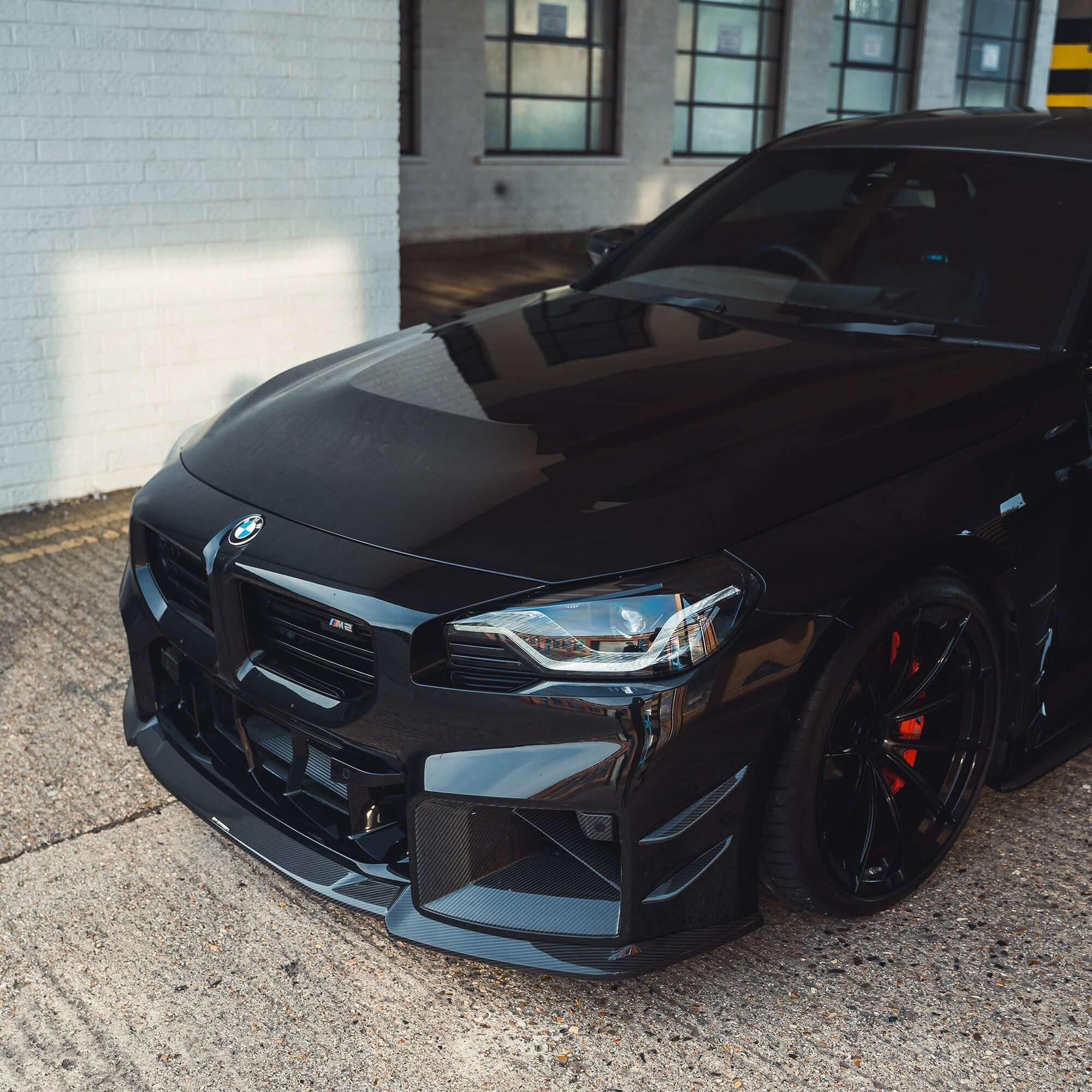 BMW G87 M2 Carbon Fibre Front Splitter enhancing aggressive front view of black BMW M2.