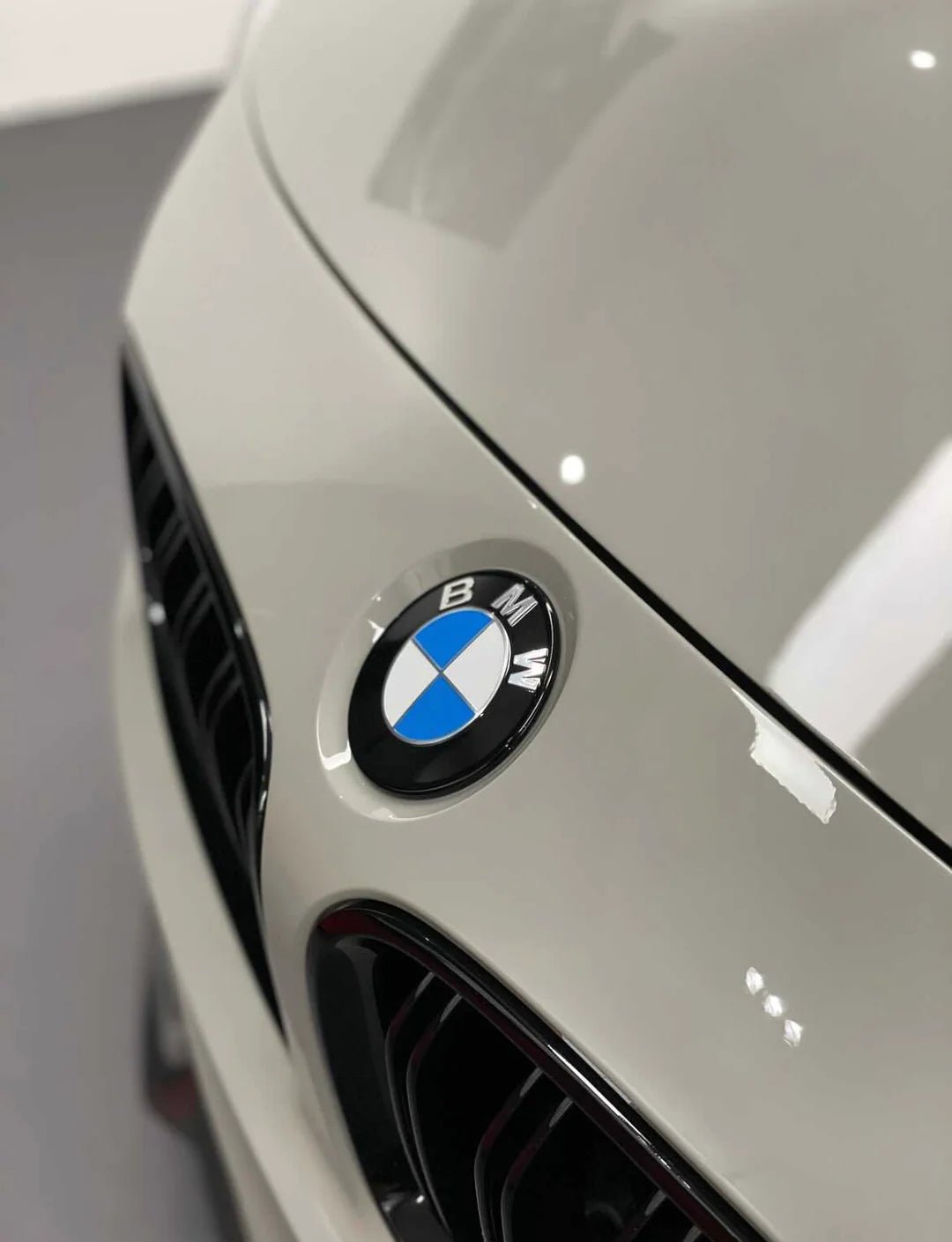 Close-up of BMW Dechromed Roundels on car hood showcasing premium OEM black badge upgrade.