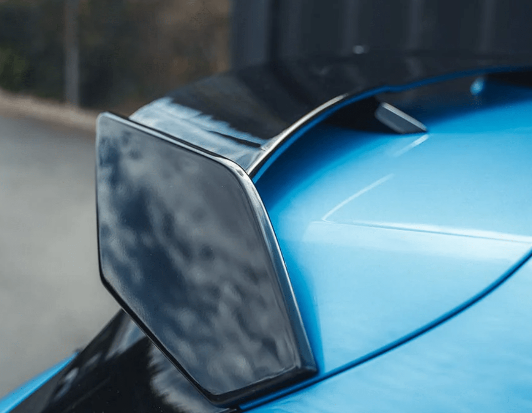 BMW F40 Roof Spoiler Gloss Black installed on a blue car showcasing its sleek design and aerodynamic shape.