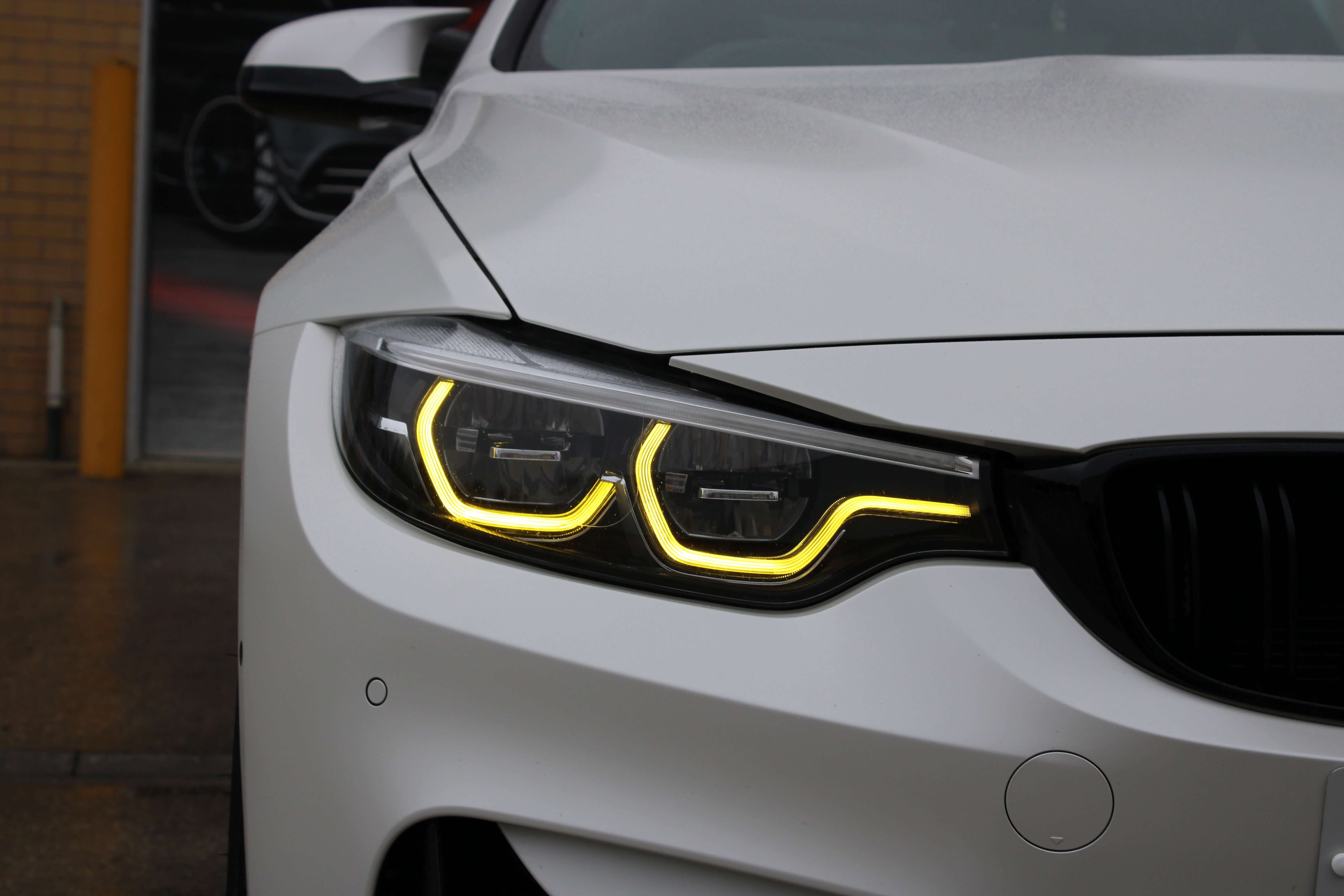 BMW Yellow DRL Modules installed on a white BMW, showcasing aggressive yellow daytime running lights.