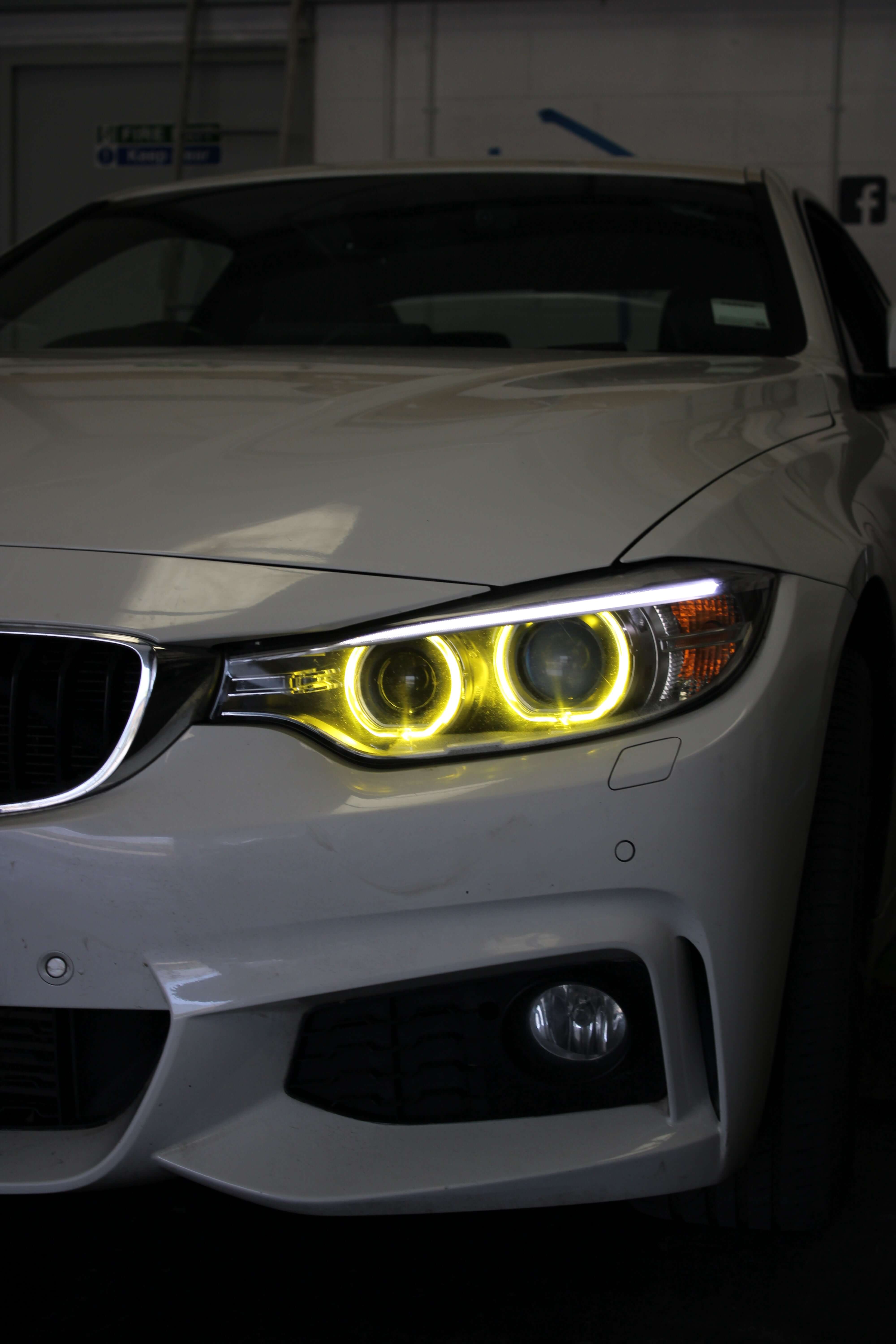BMW Yellow DRL Modules installed on a white BMW model, showcasing bright yellow daytime running lights.