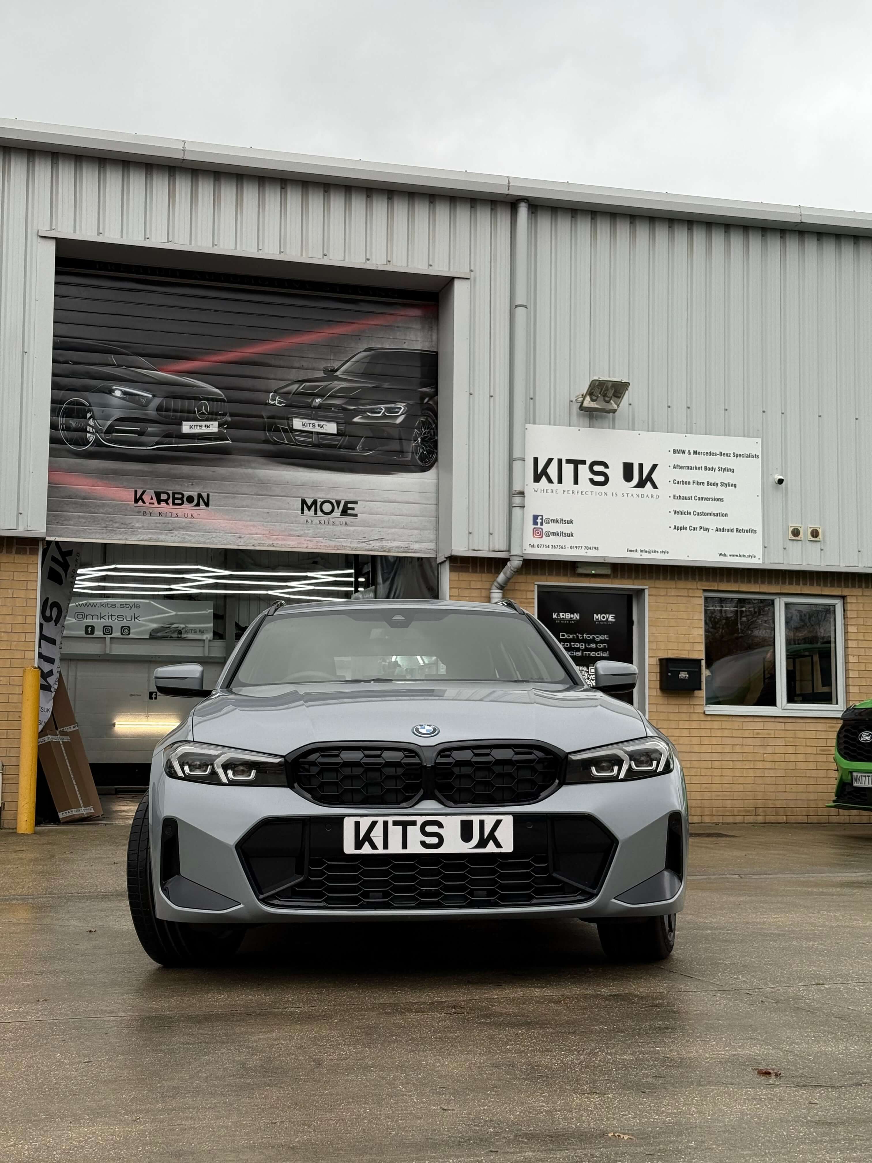 BMW G20 LCI gloss black grille showcased on a gray BMW model outside KITS UK building.