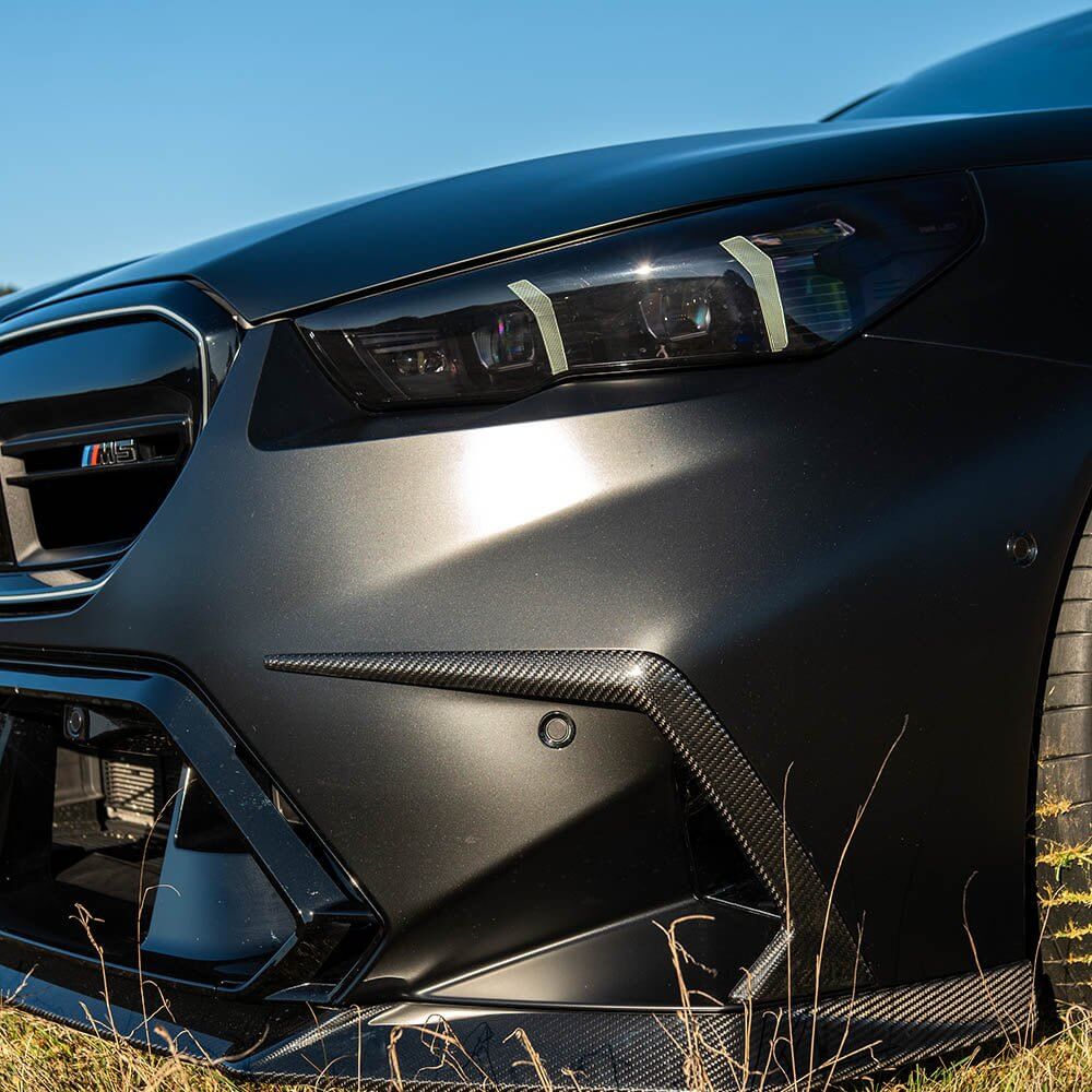 BMW G90 G99 M5 Carbon Fibre Front Bumper Trim showcasing aggressive styling and modern design.