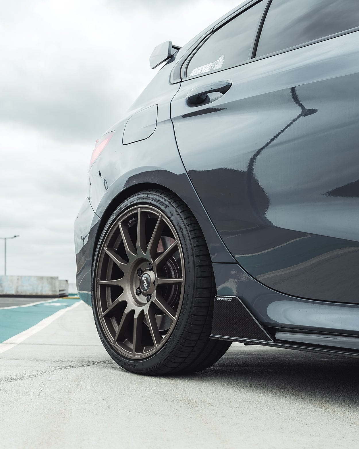 BMW F40 Carbon full body kit showcasing custom alloy wheels and side skirt on a sleek car.