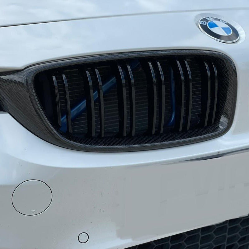 BMW F80 F82 F32 Carbon Fibre Kidney Grilles showcasing aggressive styling on a white BMW vehicle front.