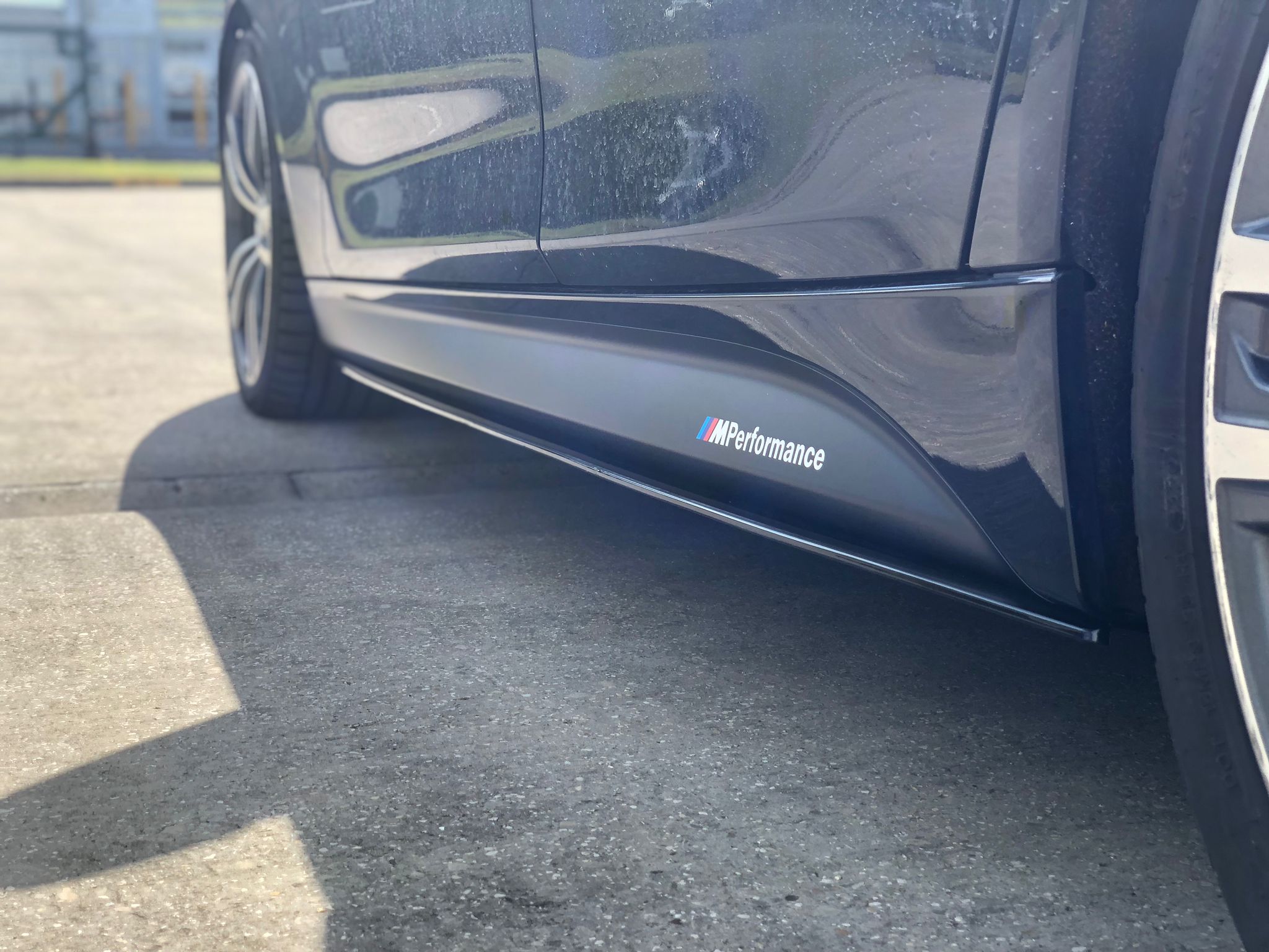 BMW F31 Touring body kit side skirt showcasing M Performance branding on a black car.