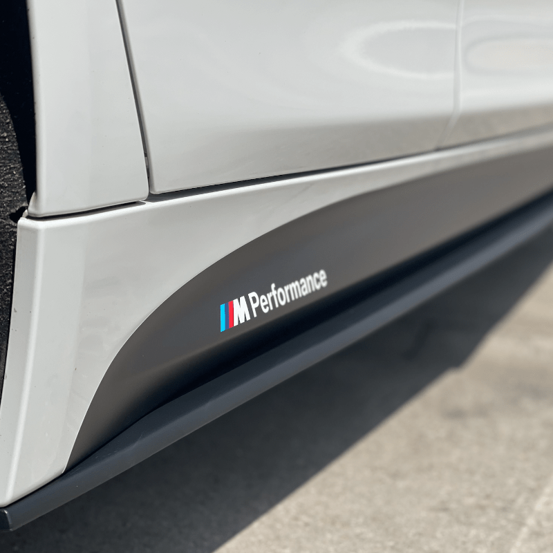 Close-up of BMW F30 F31 Side Extensions with M Performance branding on a white car.