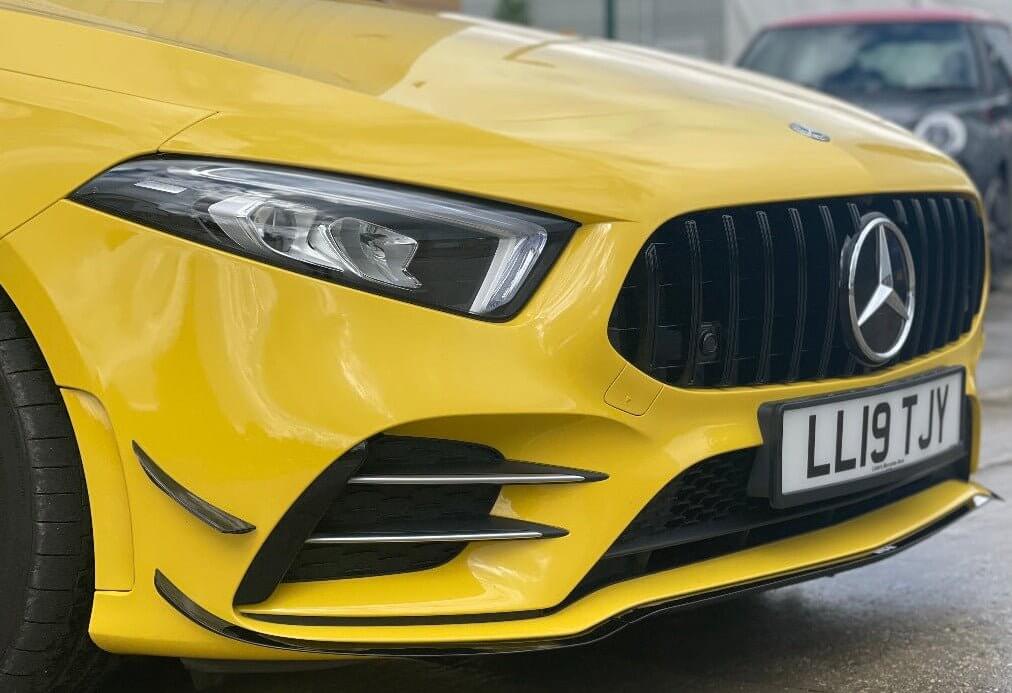 Mercedes Benz A35 aero package with gloss black accents in a bright yellow car front view.