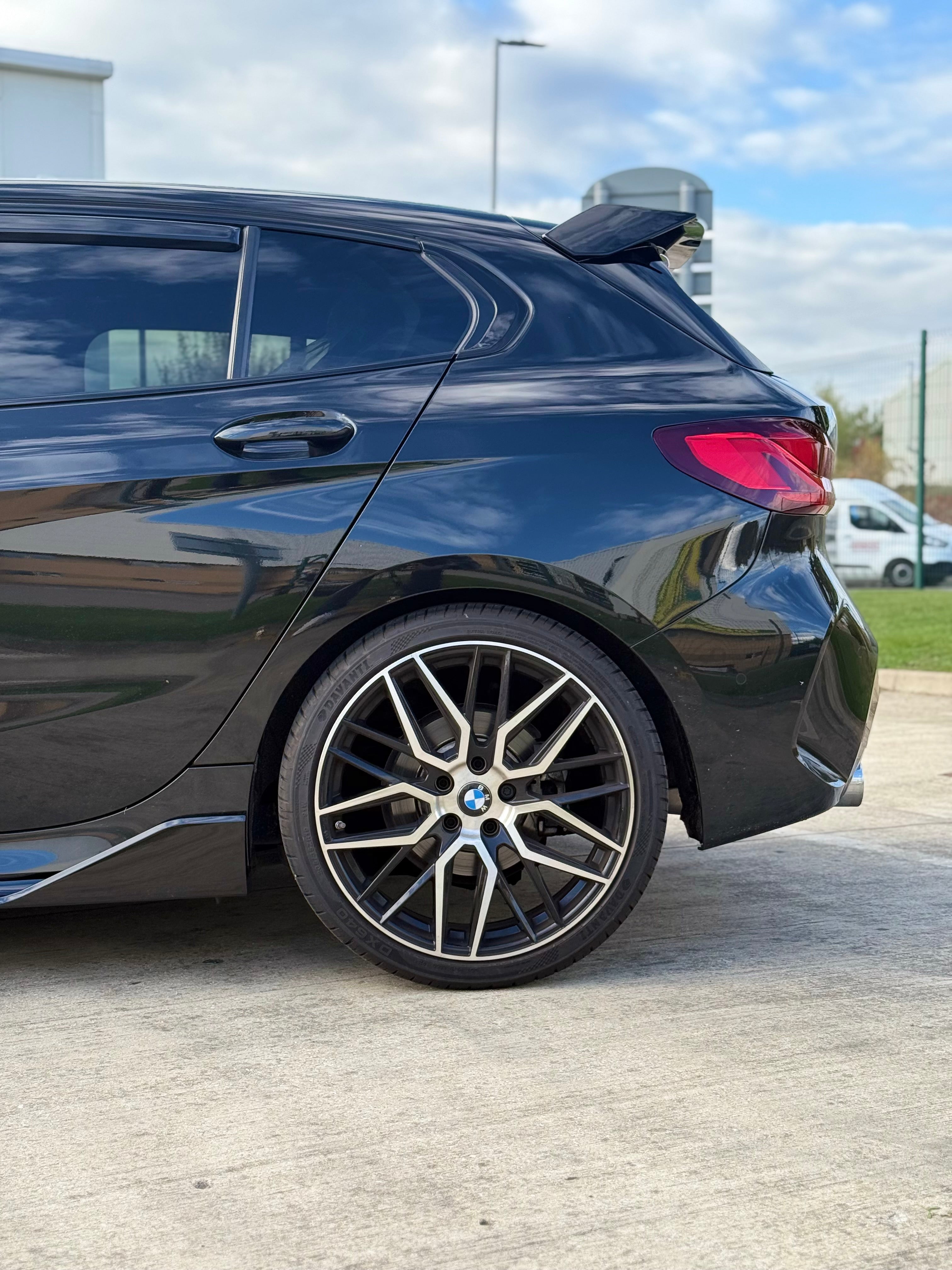 BMW F40 Gloss Black Body Kit showcased on a sleek black hatchback with stylish alloy wheels.