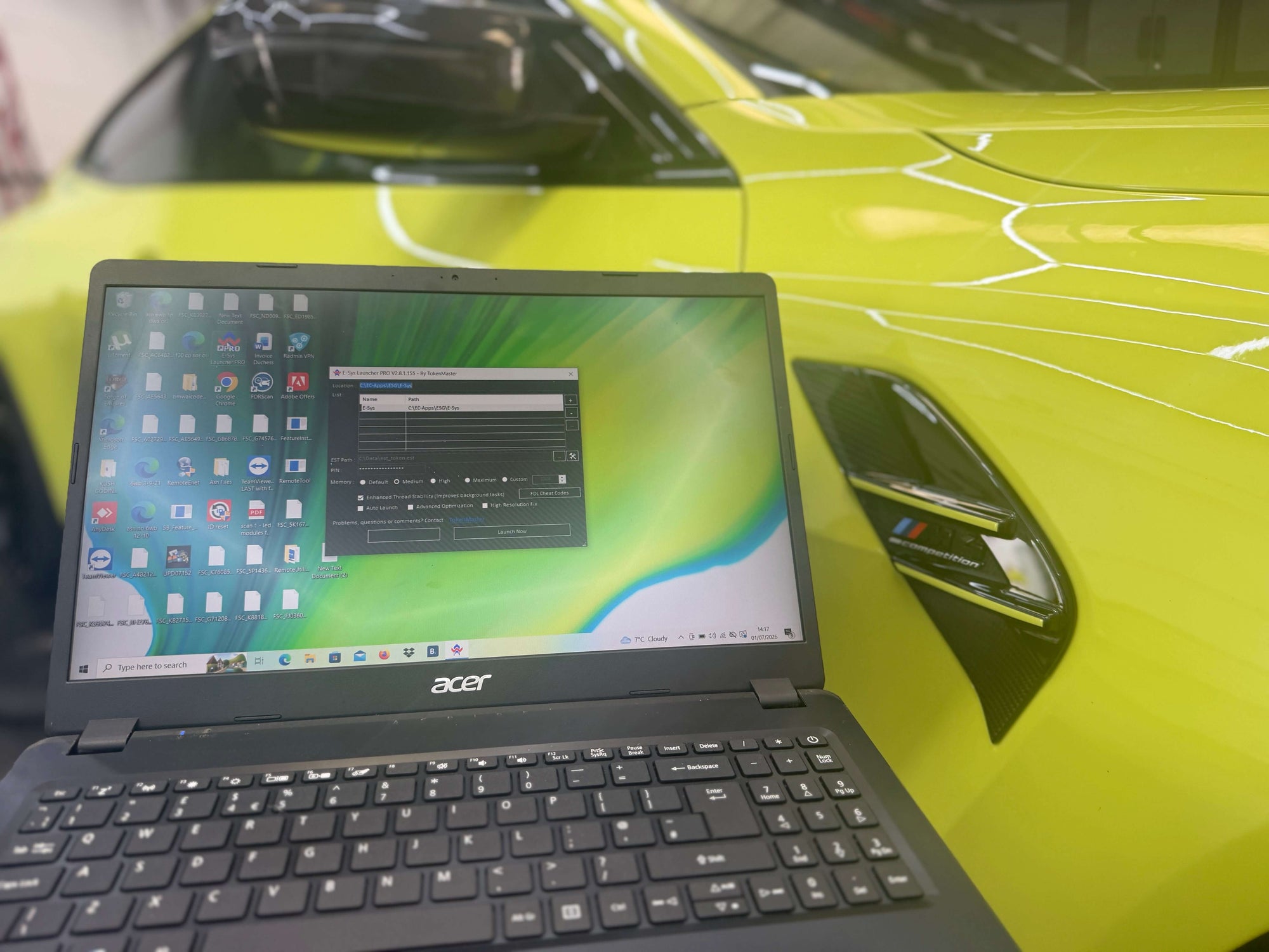 Acer laptop displaying software interface in front of a vibrant green BMW G8x - CS Flash.