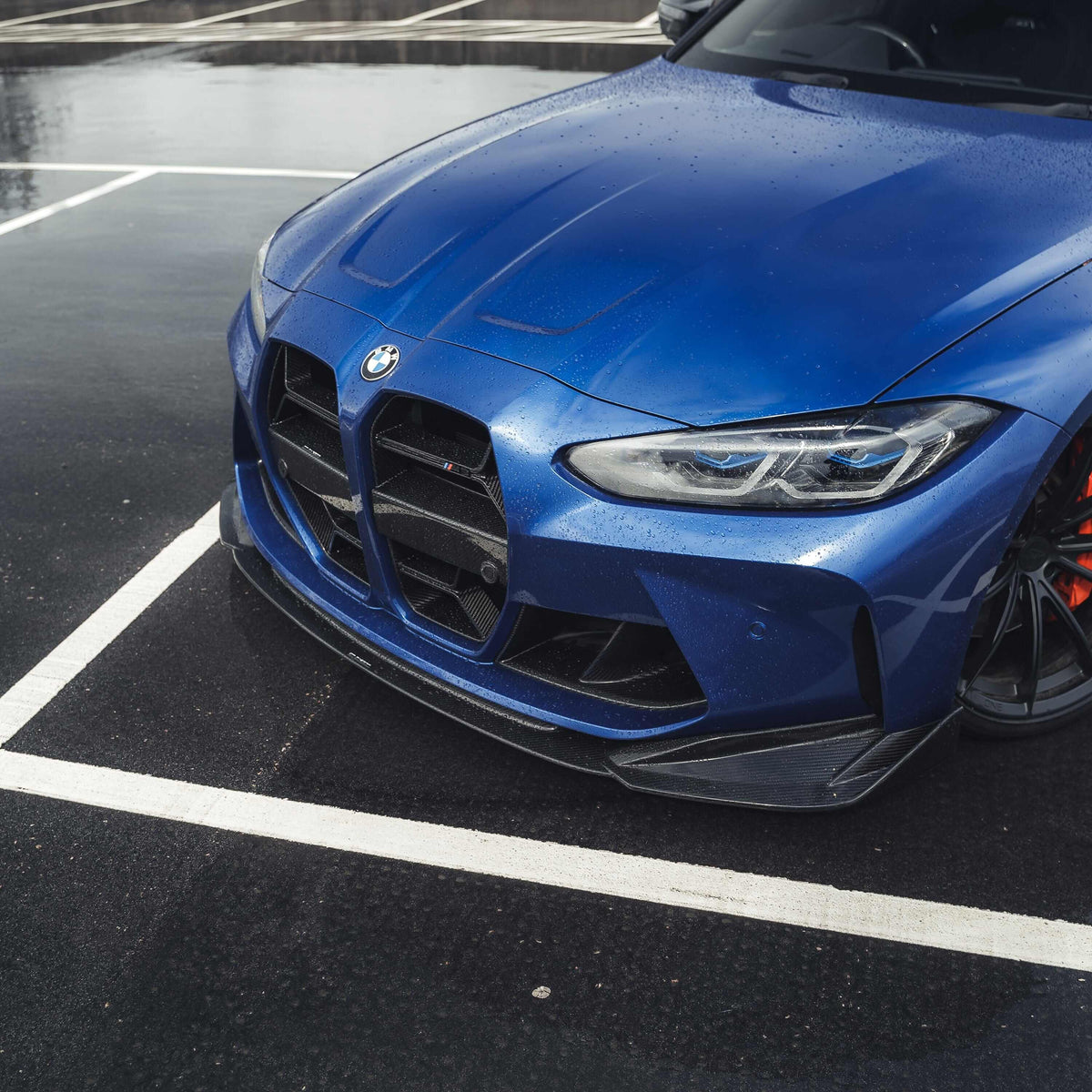 BMW M3 M4 carbon fibre splitter V2 on a blue BMW showcasing its aggressive design and performance features.
