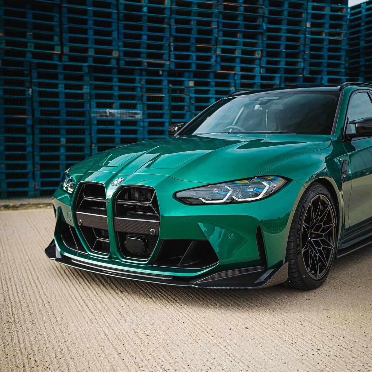 BMW M3 M4 carbon fibre splitter V2 on a green BMW M3, showcasing aggressive styling and enhanced road presence.